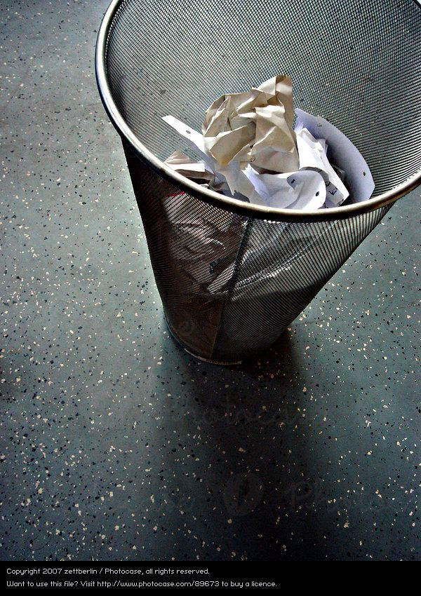 a trash can filled with crumpled paper on top of a black tablecloth covered floor