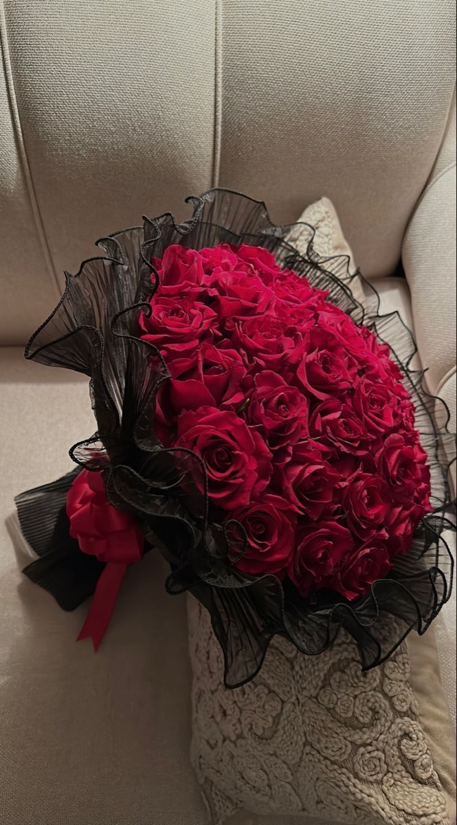 a bouquet of red roses sitting on top of a white couch next to a pillow