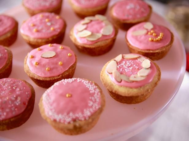 there are many pink and white cupcakes on the plate with gold sprinkles