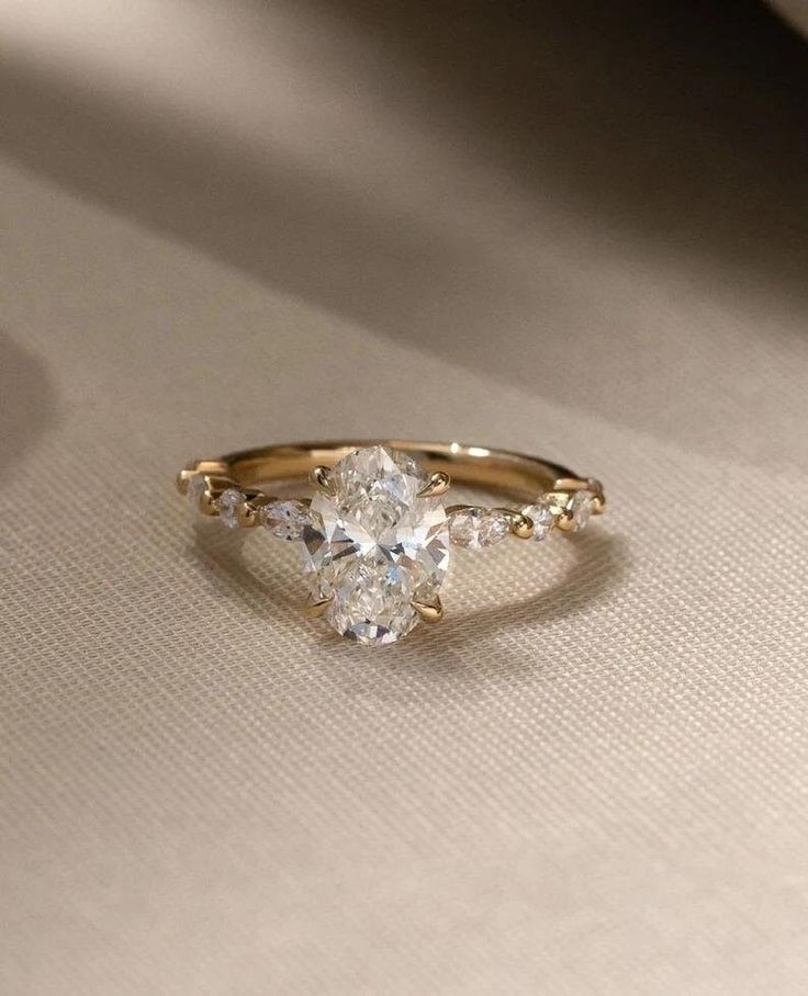 an engagement ring with three pear shaped diamonds on the side, set in yellow gold