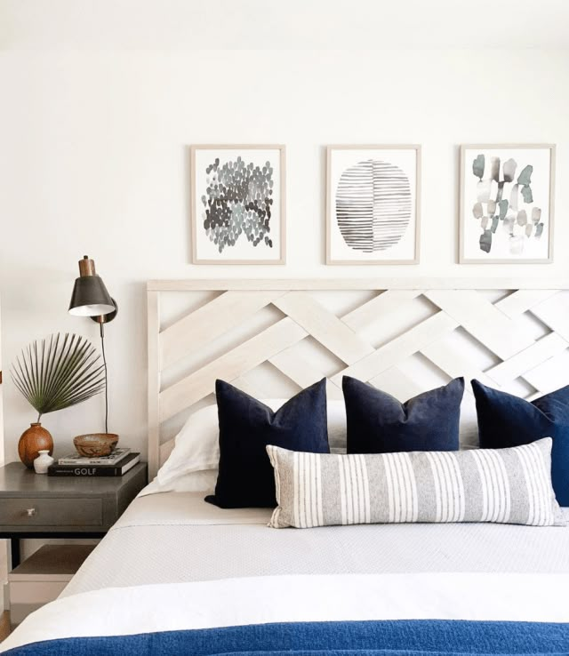 a bedroom with blue and white bedding, pictures on the wall and artwork above it