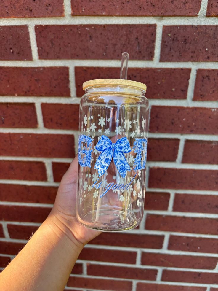 a person holding up a glass jar with blue butterflies on the side and gold rim