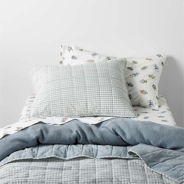 an unmade bed with blue and white sheets