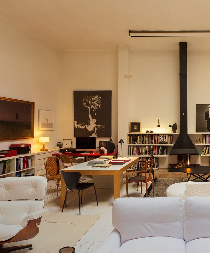 a living room filled with white furniture and lots of books on the shelves in front of it