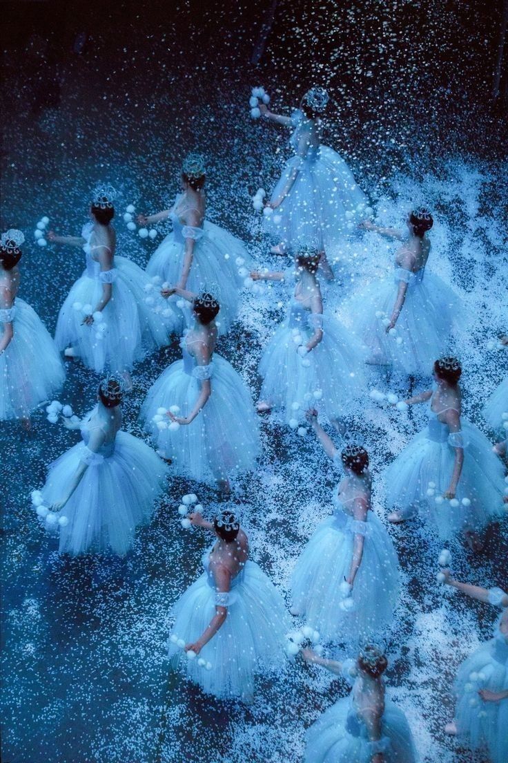 a group of ballerinas dressed in blue are dancing on the water and splashing around