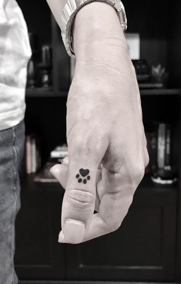 a man and woman holding hands with a small dog paw tattoo on their left hand