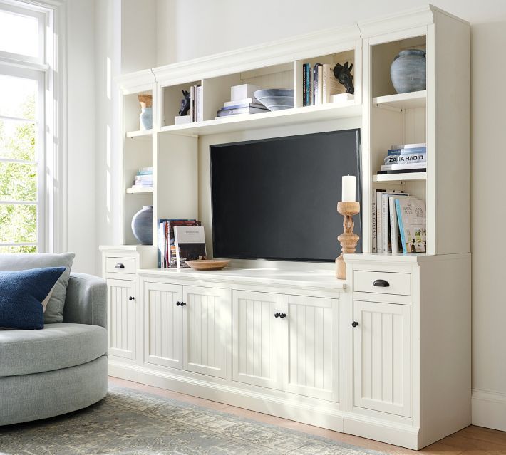 a white entertainment center with bookshelves and a large screen tv on it's side