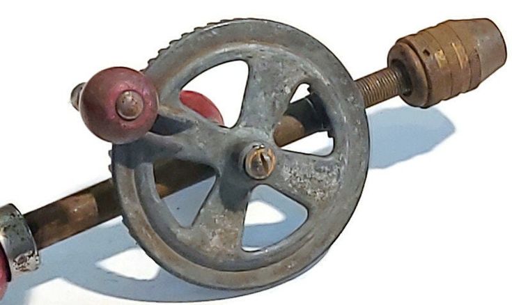 a hand holding an old metal wheel with two screws