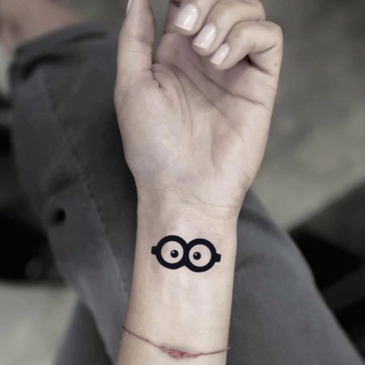 a person with a small tattoo on their wrist that has an eyeball drawn on it