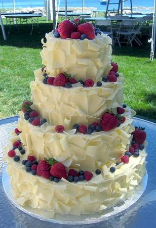 a three tiered cake with berries and blueberries on the top is sitting on a table outside