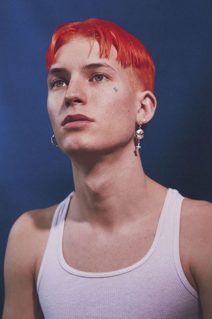 a young man with red hair and piercings on his ears, wearing a tank top