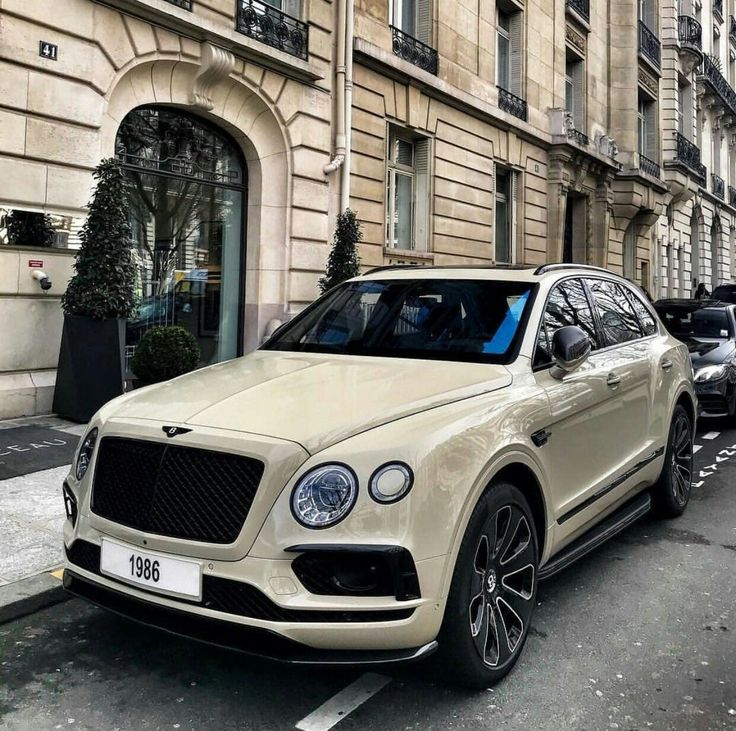 a white bentley suv parked on the side of a street