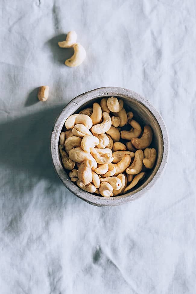 a bowl filled with cashews sitting on top of a white cloth covered table