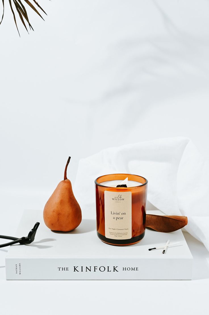 the kinfolkk home candle and pear are on top of a white book