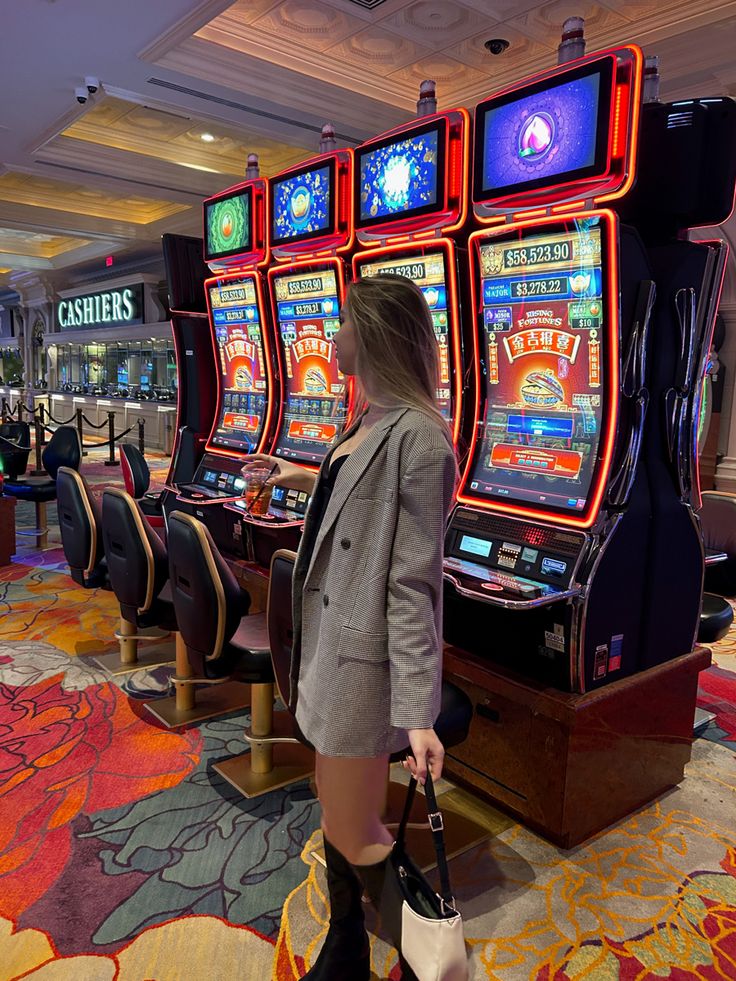 a woman standing in front of slot machines at a casino or gambling hall with her handbag