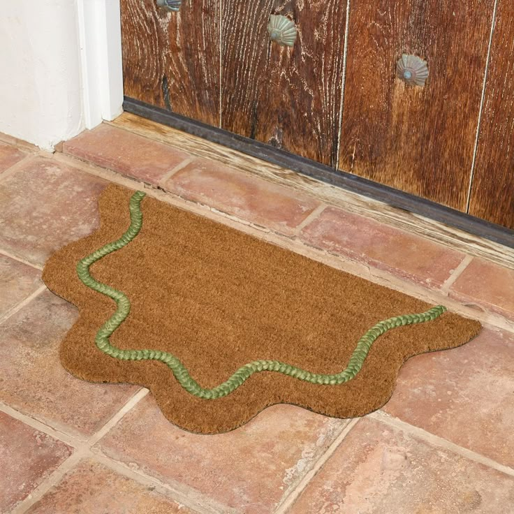 a brown door mat with a green border on the floor in front of a wooden door