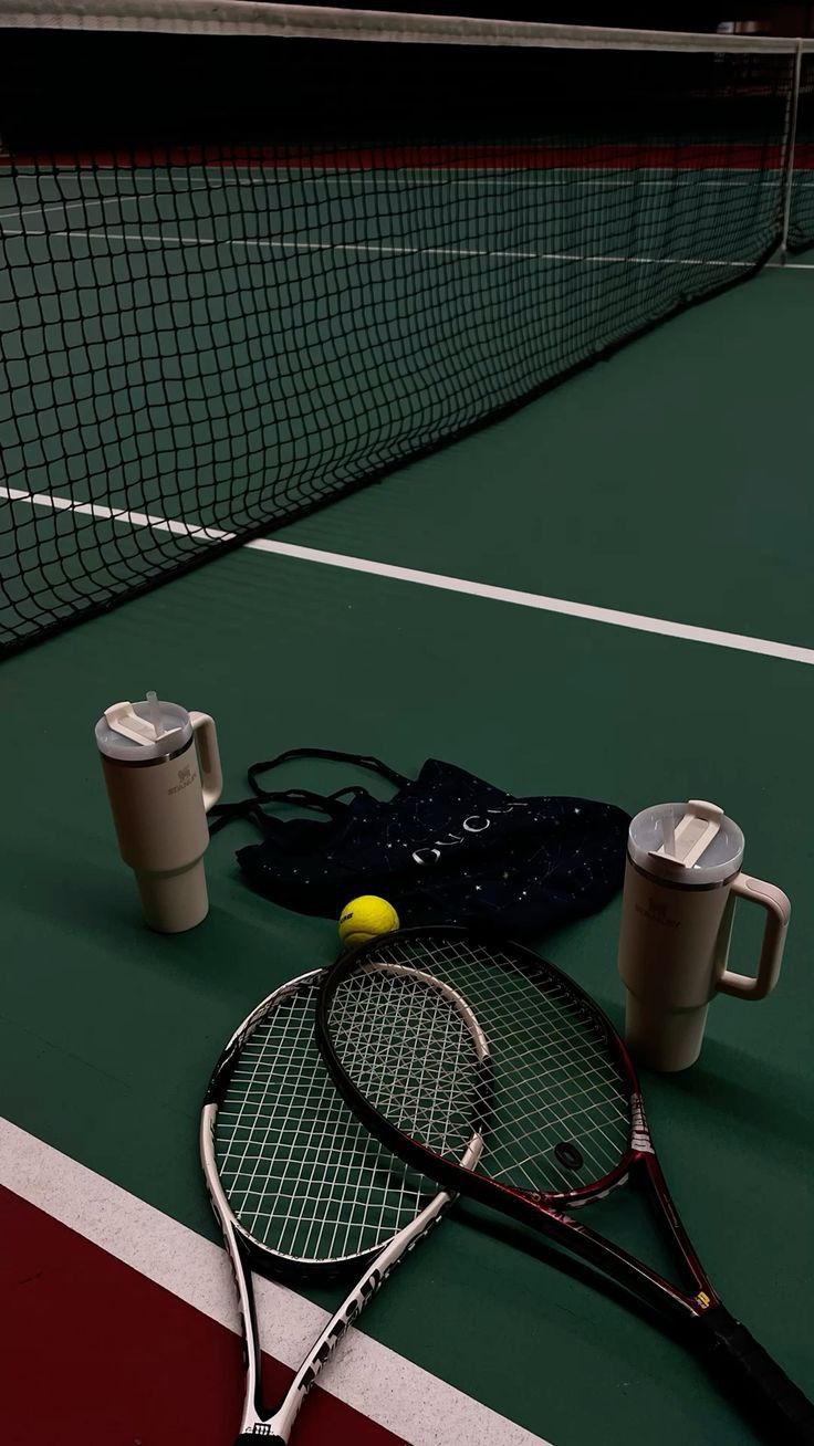 a tennis racket and two cups on a court