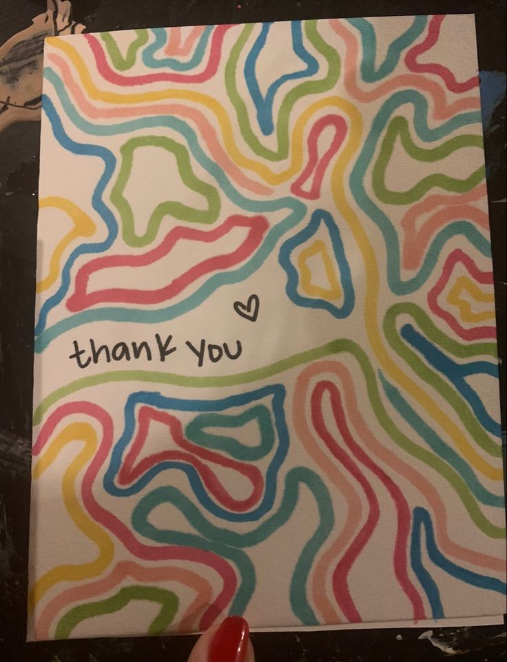 a hand holding a thank you card with colorful swirls