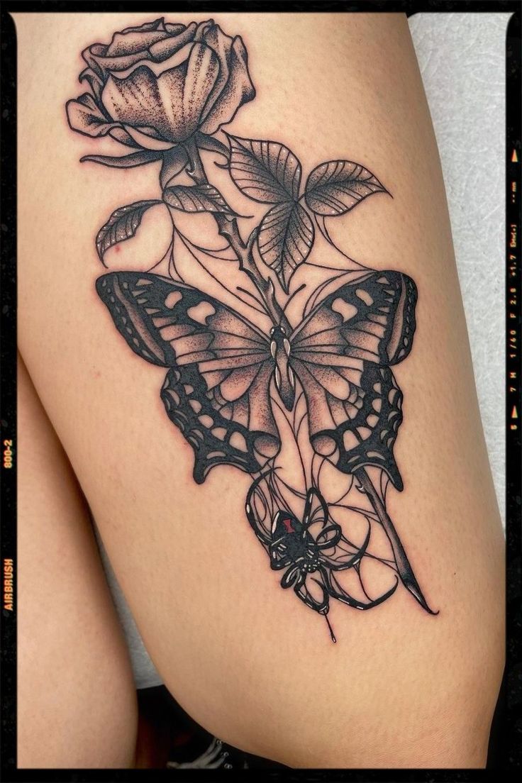 a woman's thigh with a butterfly and rose tattoo on it