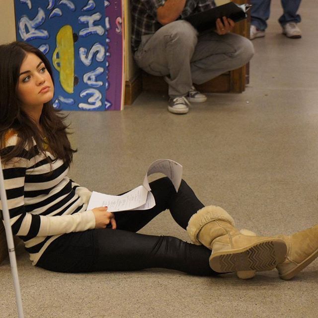 a woman sitting on the floor with her legs crossed and holding a sign in front of her