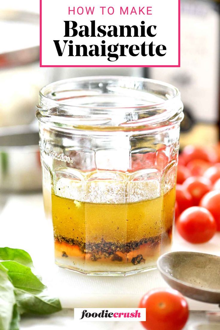 a jar filled with balsamic vinaigrete next to tomatoes and basil