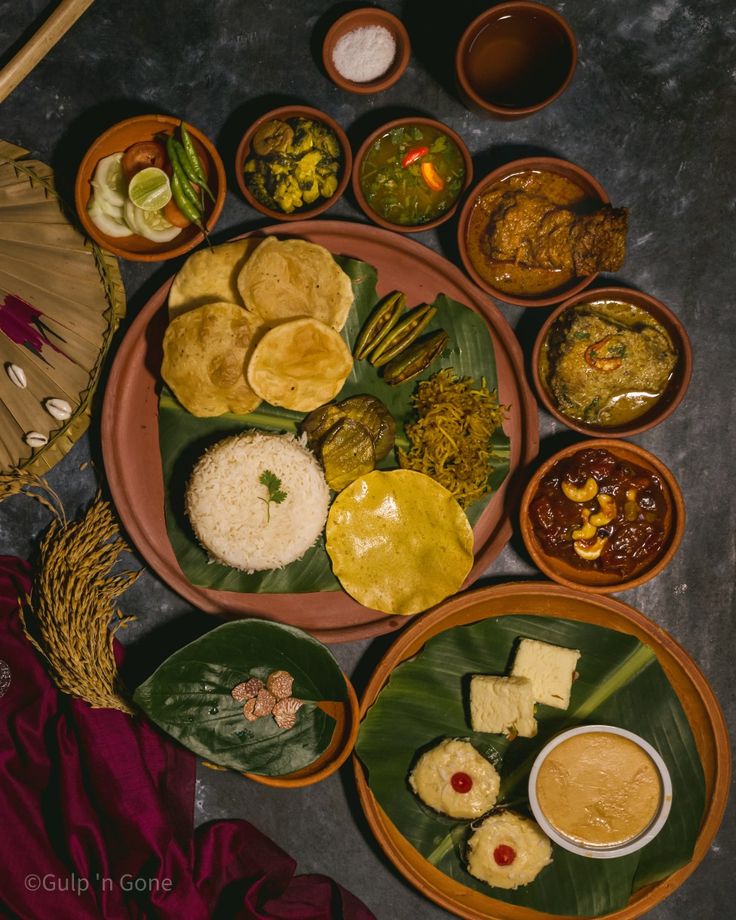 an assortment of food is displayed in bowls on a table with other foods and utensils