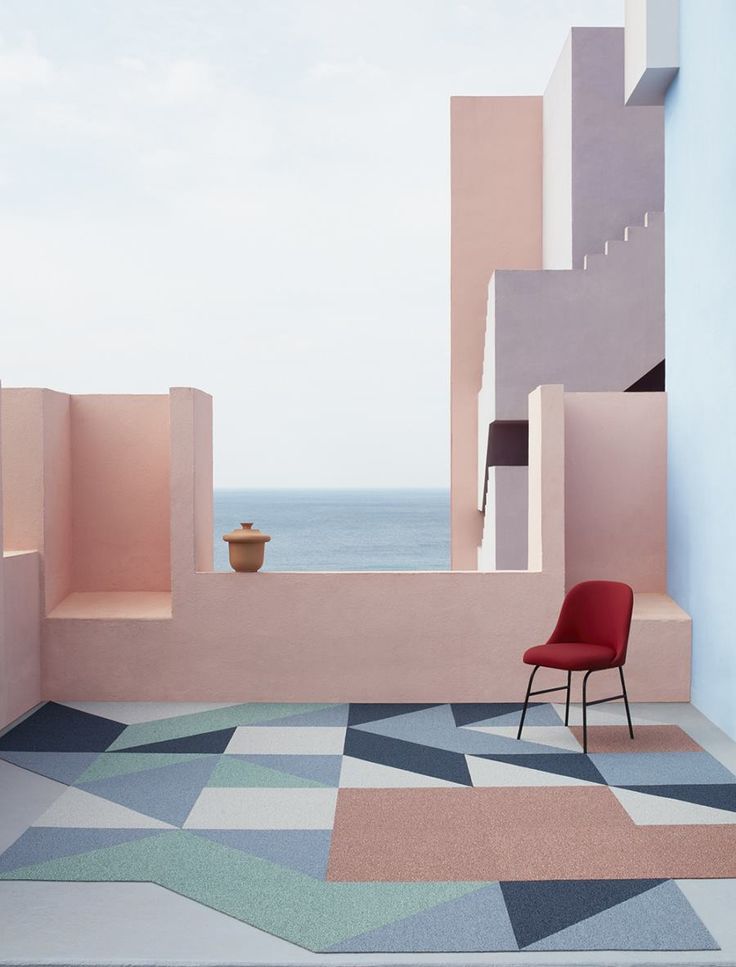 a red chair sitting on top of a tiled floor next to a wall with an ocean view