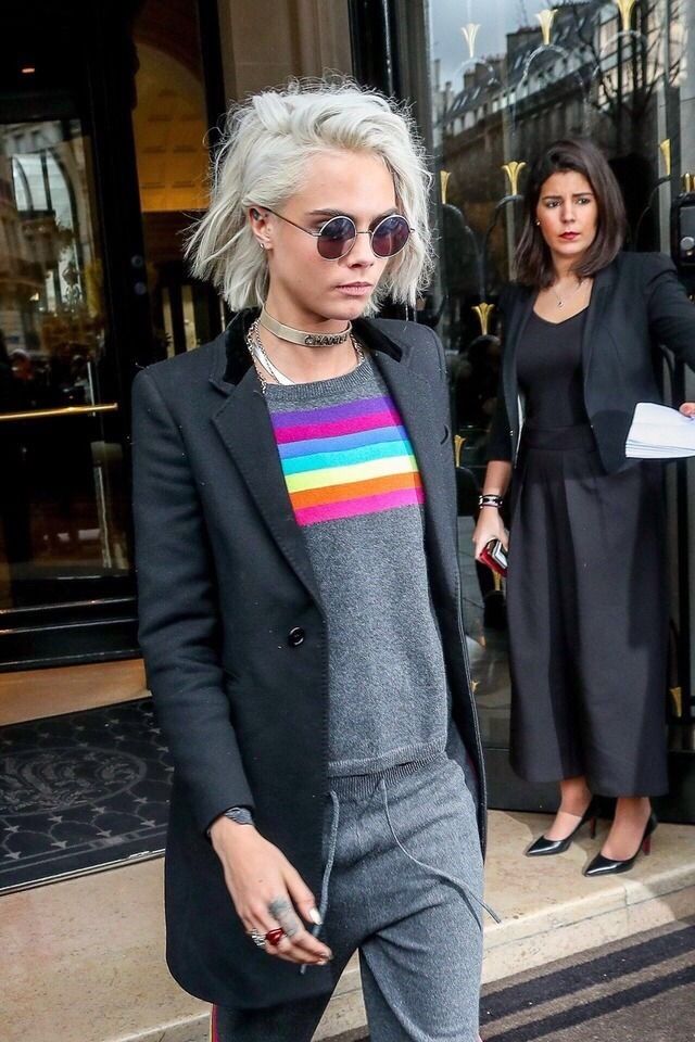 a woman with grey hair and sunglasses is walking down the street