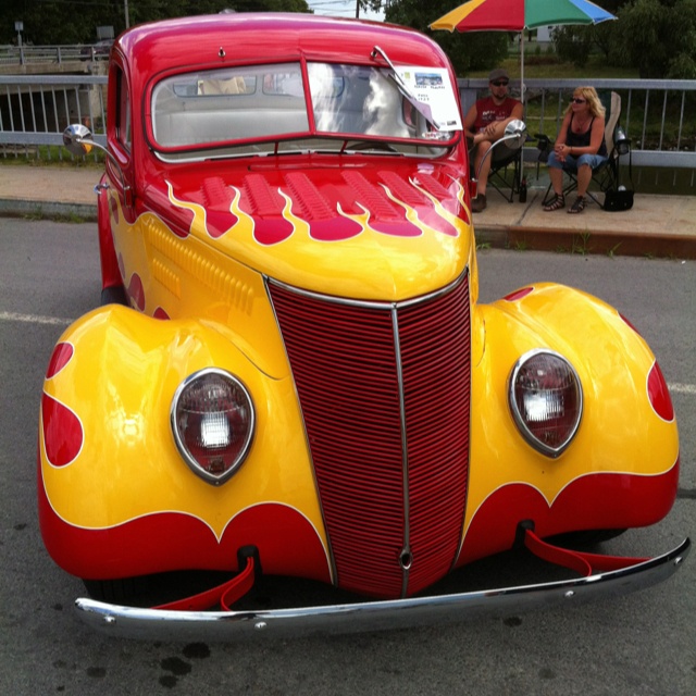 an old yellow and red car with flames painted on it's front grills