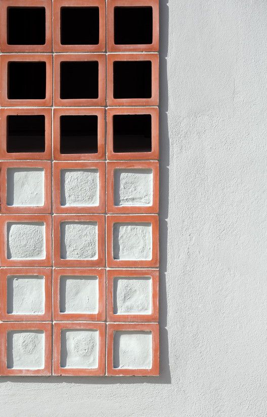 an orange and white wall with some squares on it's side, in front of a building