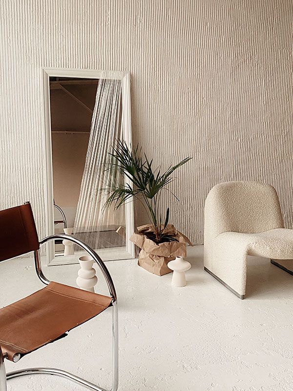 two chairs and a mirror in a room with white walls, one chair has a brown leather seat