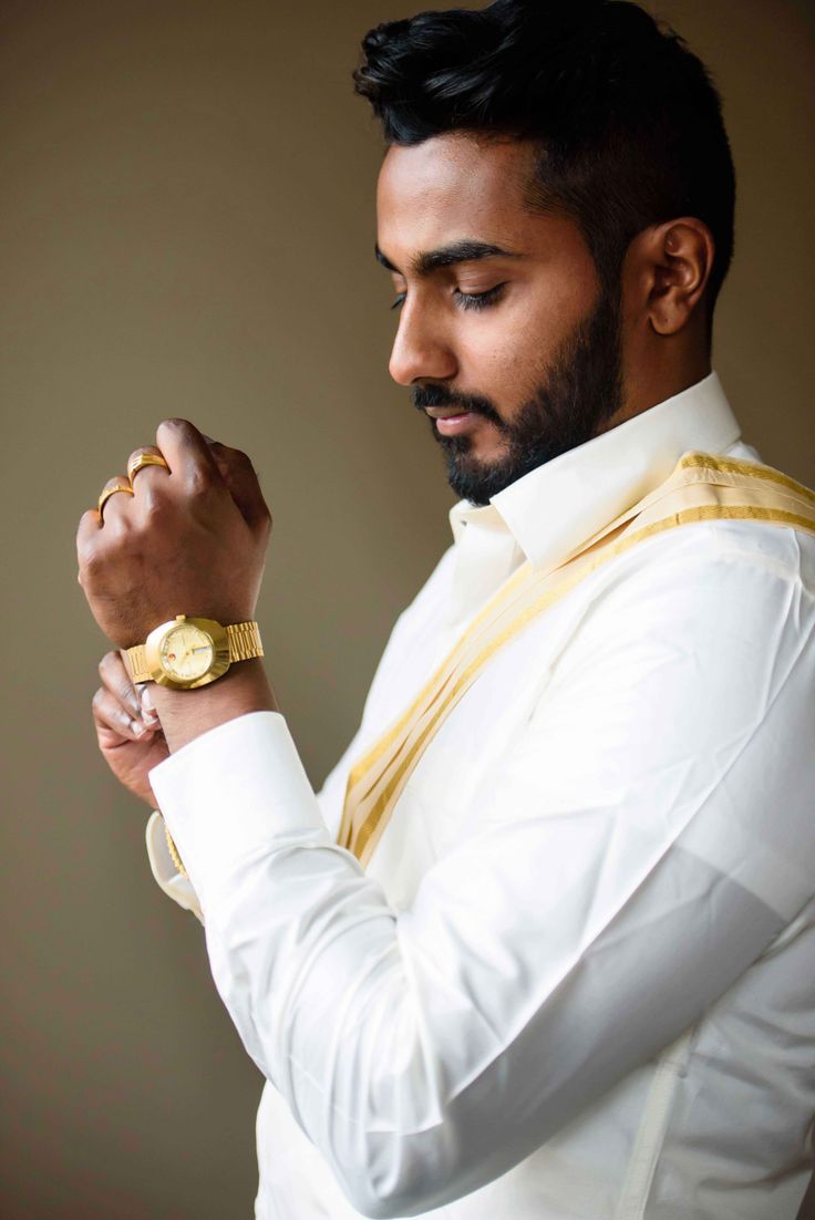 a man wearing a white shirt and gold tie with his hands clasped to his chest