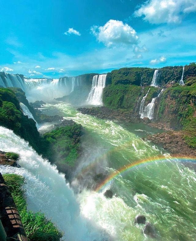 a rainbow in the sky over a waterfall