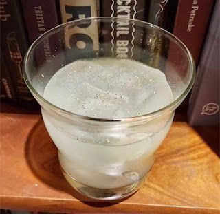 a glass filled with water sitting on top of a wooden table next to bookshelves