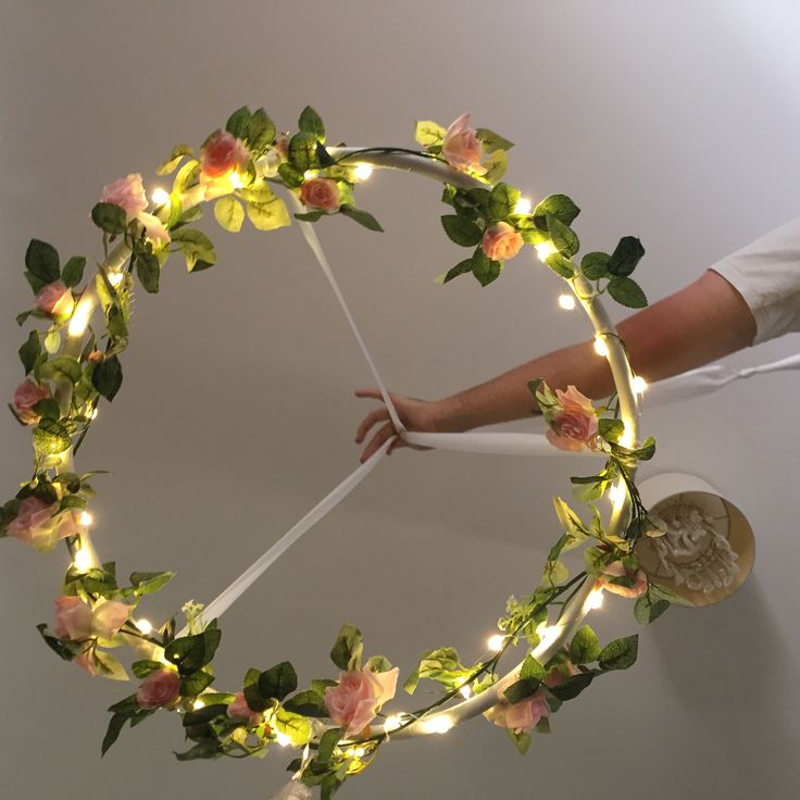 a wreath made out of flowers and lights is being held by someone's hand