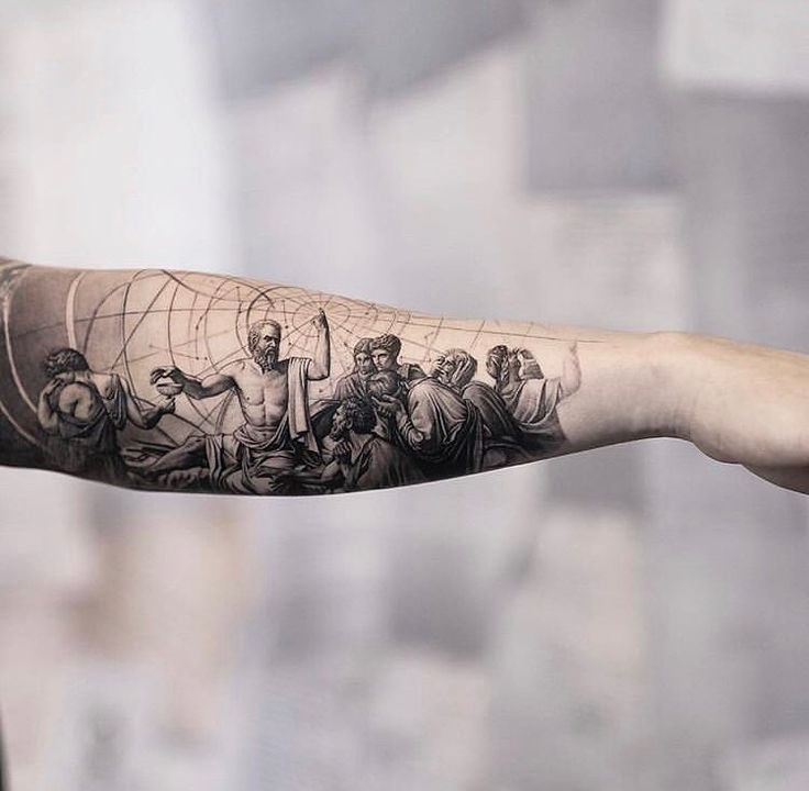 a man's arm with an image of people on it and a spider web in the middle