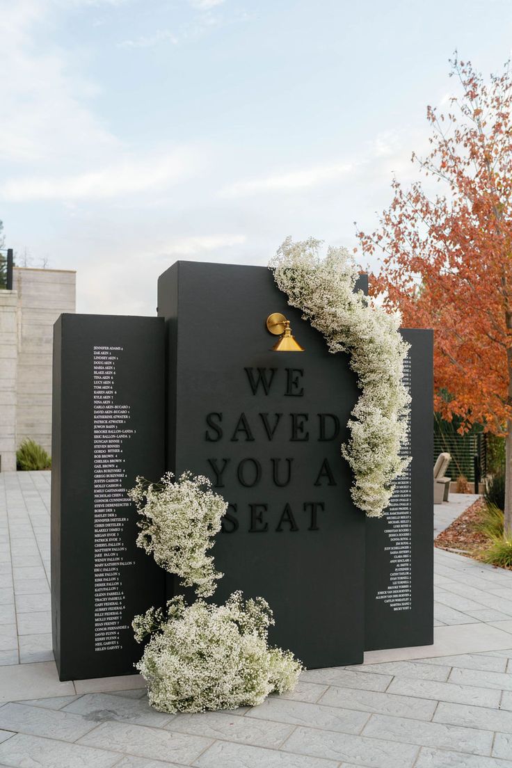 the memorial wall is decorated with white flowers and greenery that reads, we saved you at least