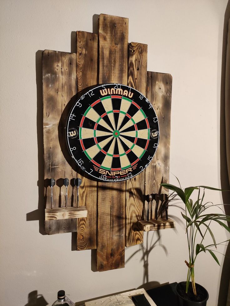 a dart board mounted to the side of a wall next to a potted plant