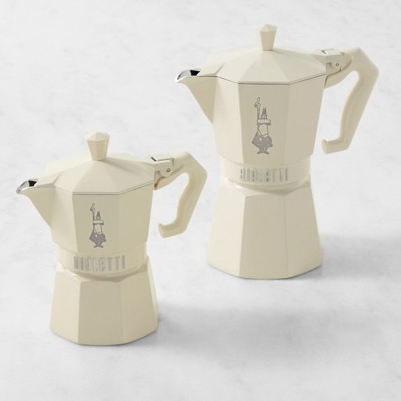 two white coffee pots sitting next to each other on top of a snow covered ground