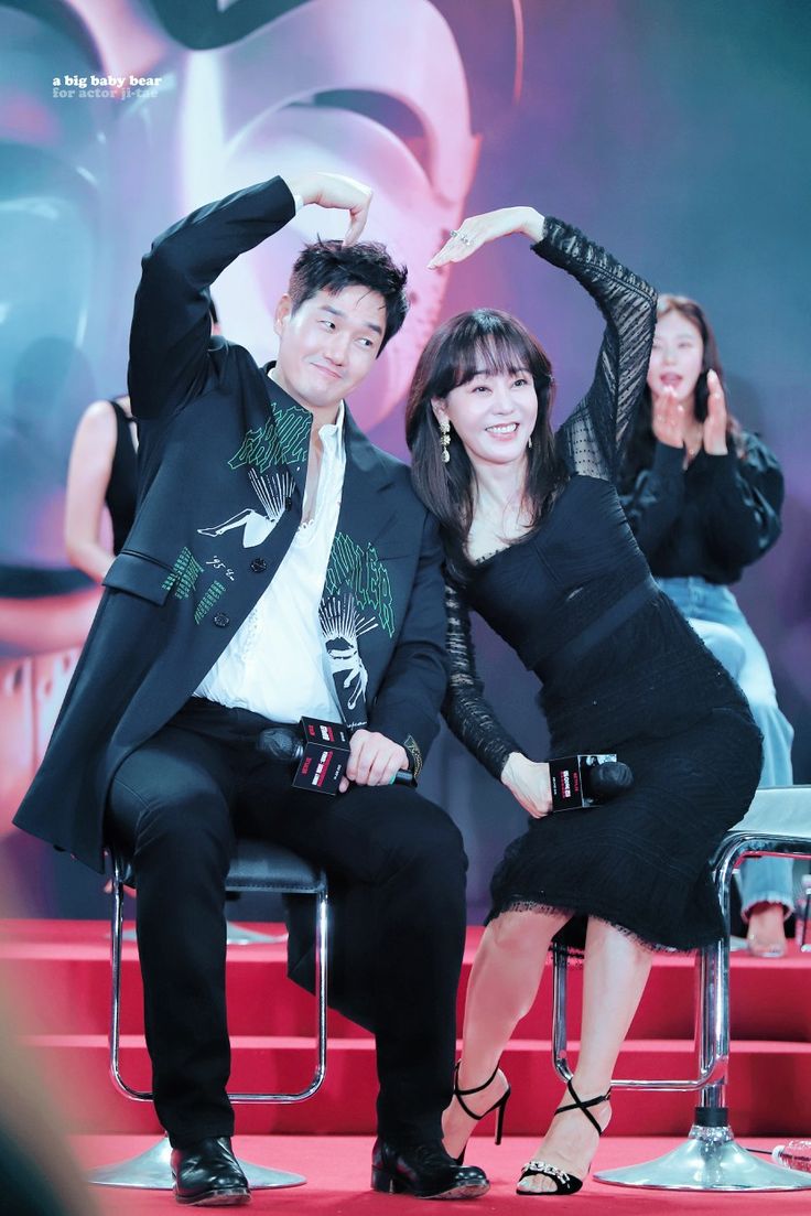 a man and woman posing for a photo on stage with their hands in the air