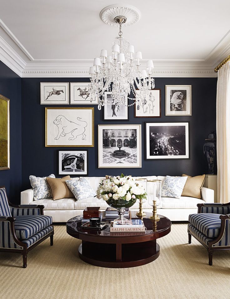 a living room with blue walls and pictures on the wall above the couches,