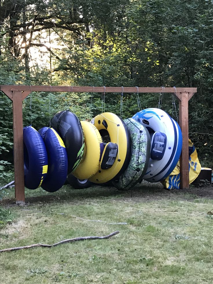 a bunch of life vests are hanging on a rack in the grass near some trees