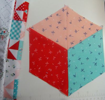 a piece of fabric is laying on top of a quilting ruler and next to it are two hexagons