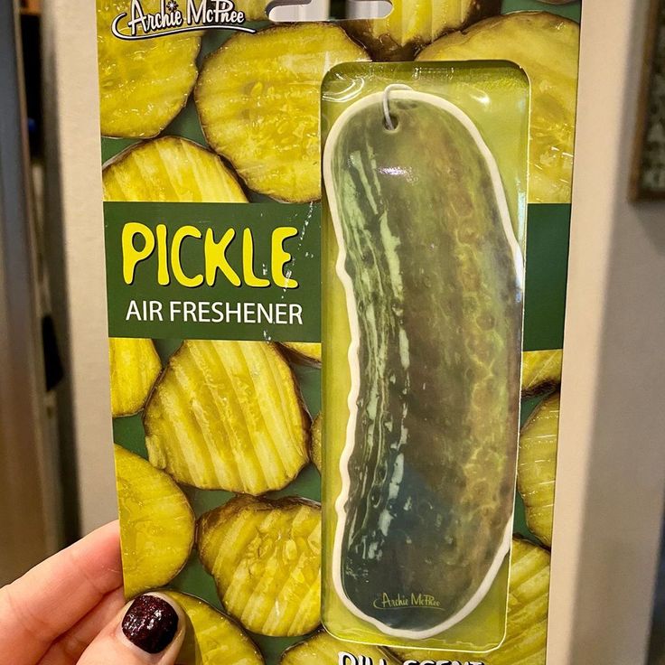 a package of pickle air freshener is being held by a woman's hand