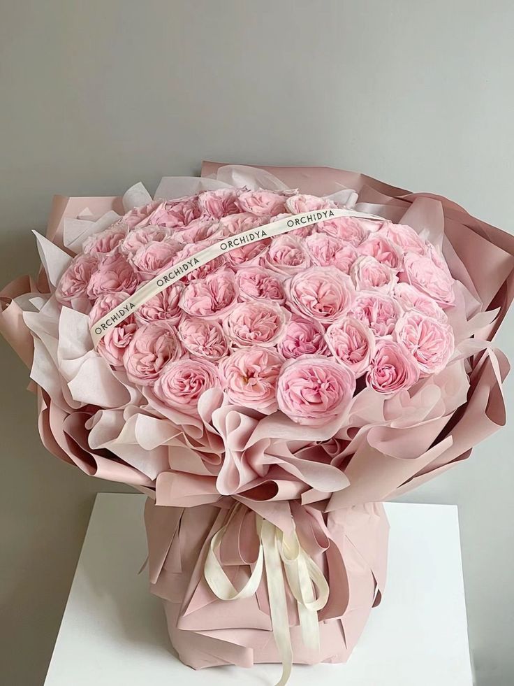 a large bouquet of pink roses is wrapped in paper