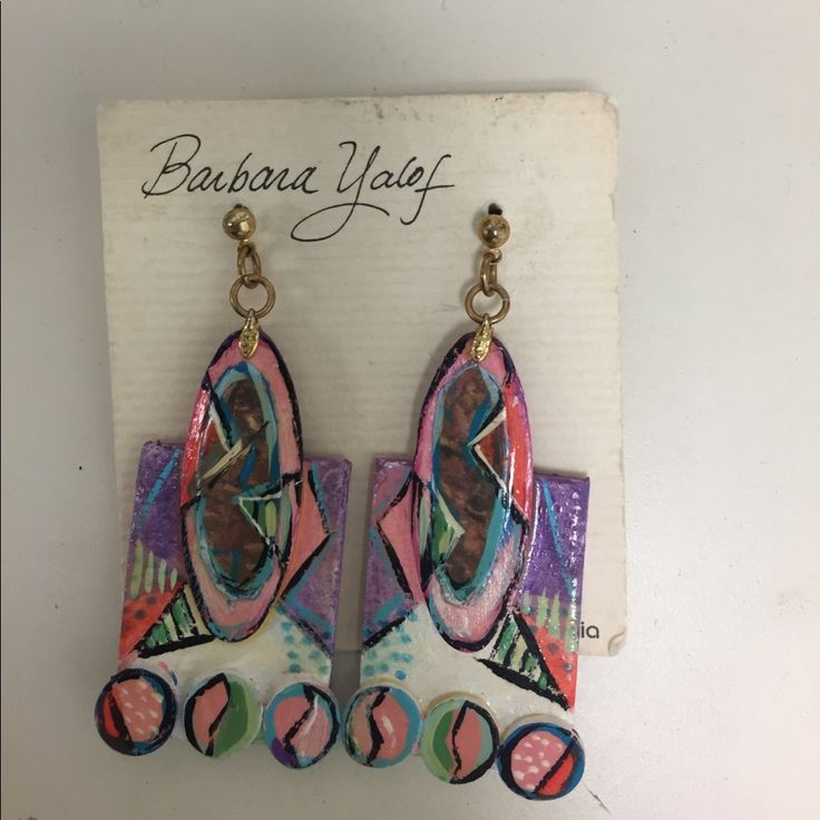 a pair of colorful earrings hanging from a hook on a white background with the words barbara yolff written below it