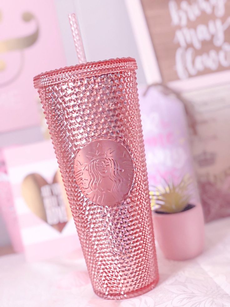 a pink starbucks cup sitting on top of a table