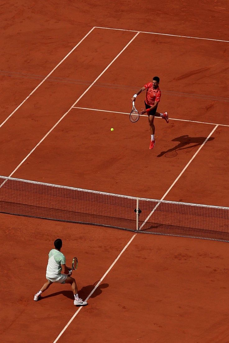 two men playing tennis on a clay court