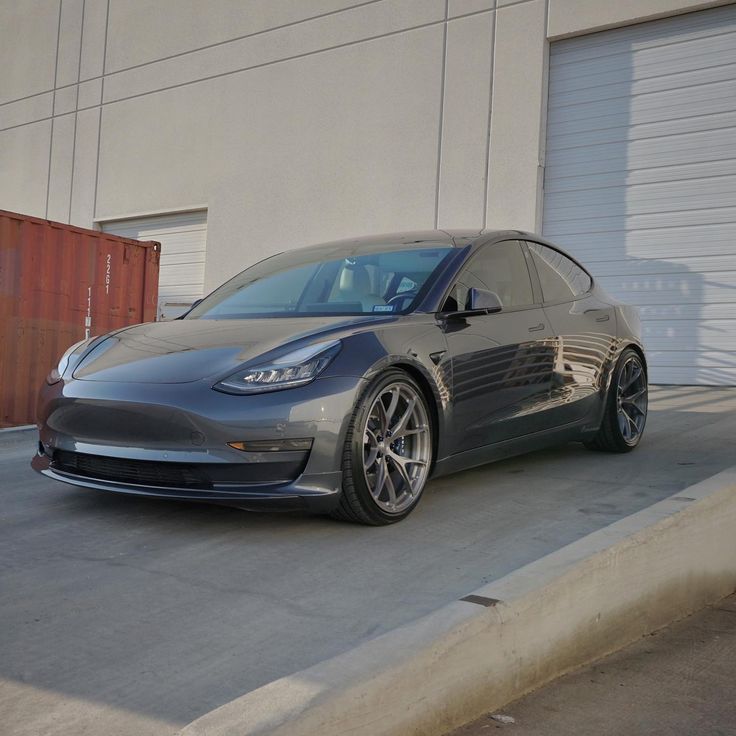 an electric car parked in front of a garage