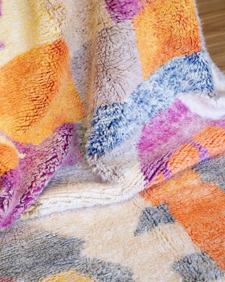 a multicolored blanket sitting on top of a wooden floor